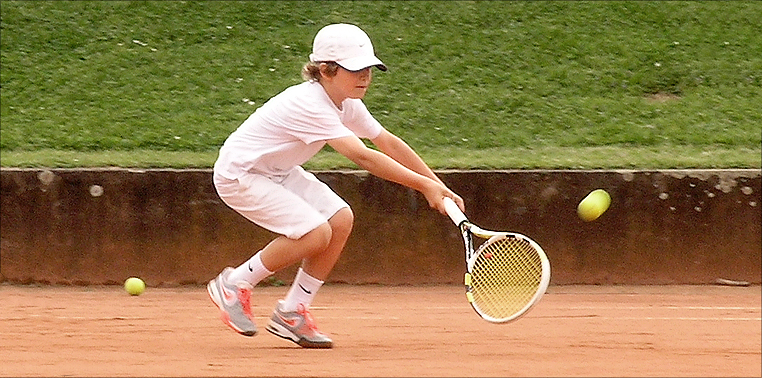 8-jähriger Tennisspieler Denis Robin Wolf, der sich nach einem Ball streckt